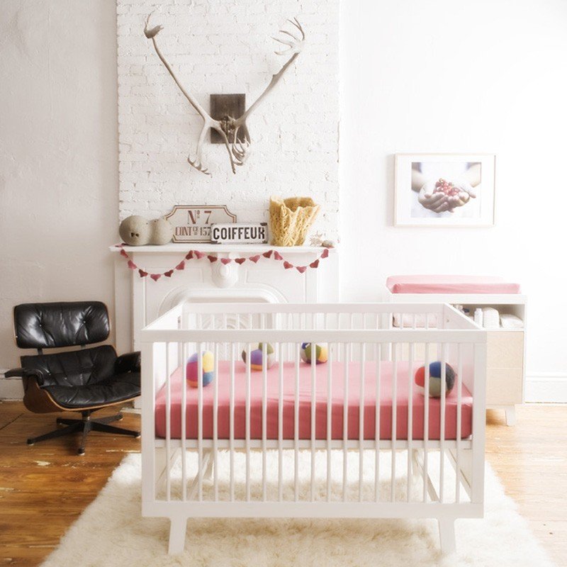 modern white crib with soft red bedding. 