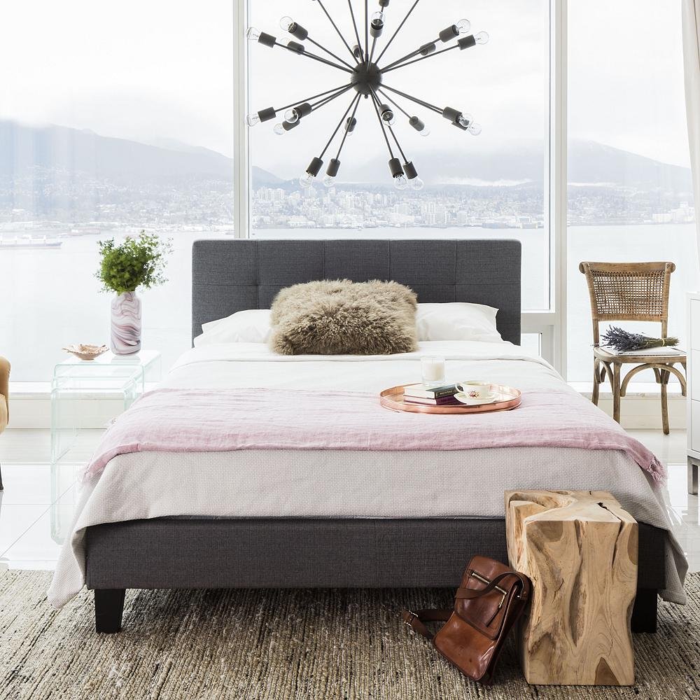 modern dark grey bed with chandelier over it.